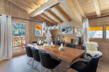 This stunning chalet boasts a spacious dining area with a live-edge wooden table, perfect for enjoying meals with breathtaking mountain views.
