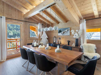This stunning chalet boasts a spacious dining area with a live-edge wooden table, perfect for enjoying meals with breathtaking mountain views.