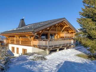 Discover the charm of this stunning wooden chalet nestled in a snowy landscape.
