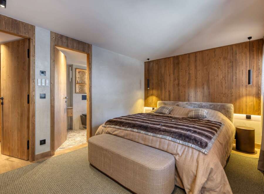 Experience luxury in this stunning bedroom featuring a cozy bed with a plush fur blanket and stylish plaid pillows.