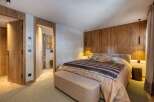 Experience luxury in this stunning bedroom featuring a cozy bed with a plush fur blanket and stylish plaid pillows.