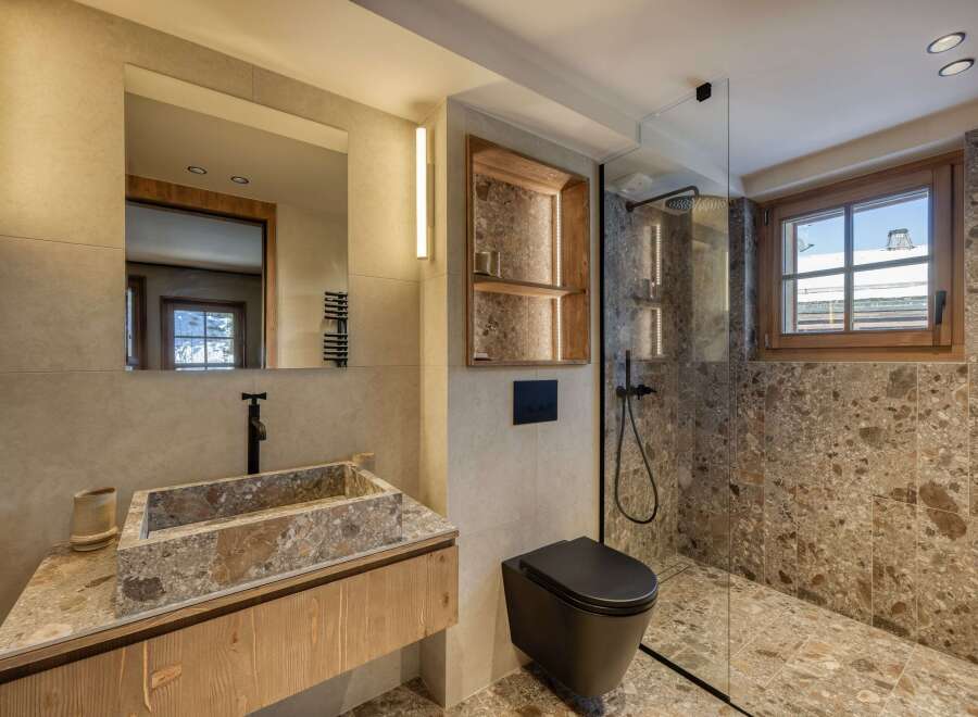 This luxurious bathroom features a stunning stone sink and countertop, complemented by a sleek black faucet.