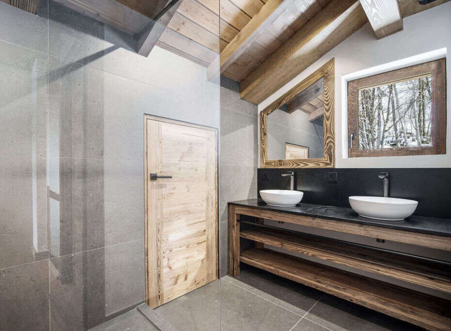 This stunning bathroom boasts a double vanity with sleek sinks and a rustic wooden frame, creating a perfect blend of modern and traditional design.