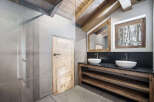 This stunning bathroom boasts a double vanity with sleek sinks and a rustic wooden frame, creating a perfect blend of modern and traditional design.