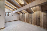 This stunning attic conversion boasts exposed wooden beams and reclaimed wood paneling, creating a rustic-chic atmosphere.