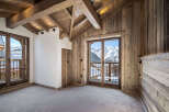 This stunning chalet boasts a spacious bedroom with floor-to-ceiling windows offering breathtaking mountain views.