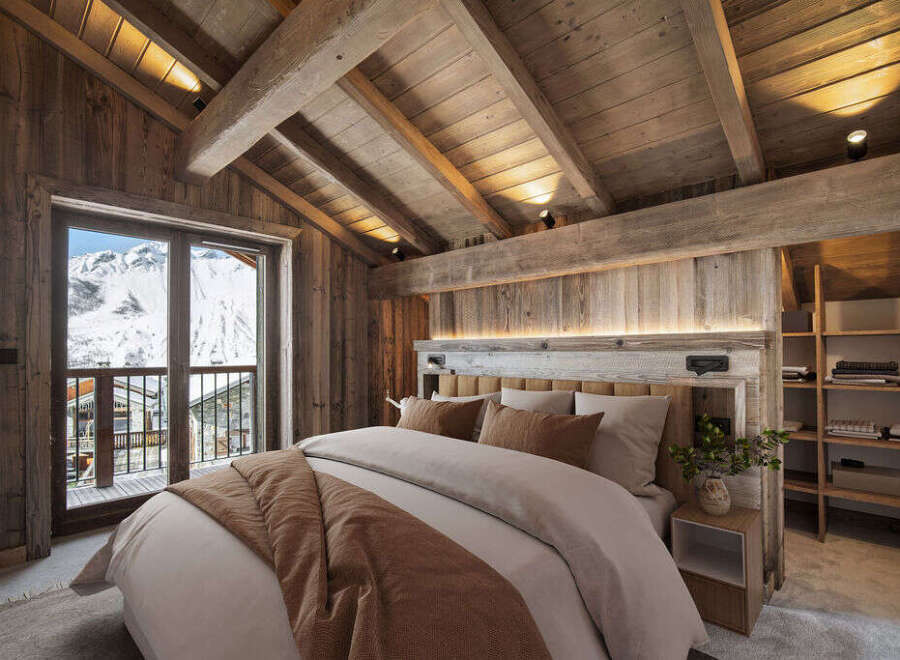 Cozy chalet bedroom with stunning mountain views and rustic wooden beams.