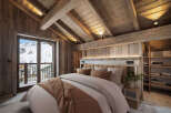 Cozy chalet bedroom with stunning mountain views and rustic wooden beams.