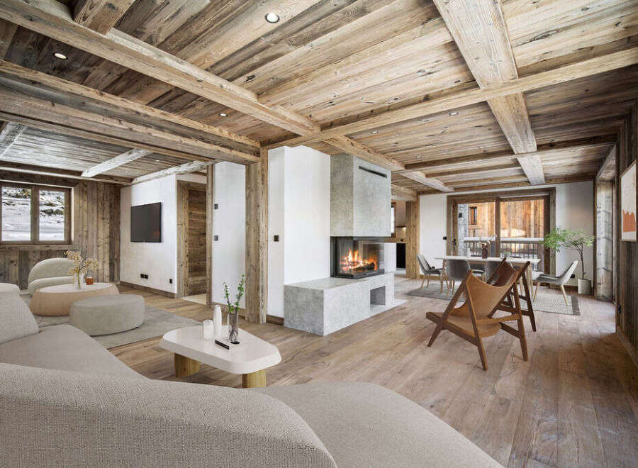 This stunning chalet boasts a spacious open-plan living area with exposed wooden beams and a cozy fireplace, creating a warm and inviting atmosphere.