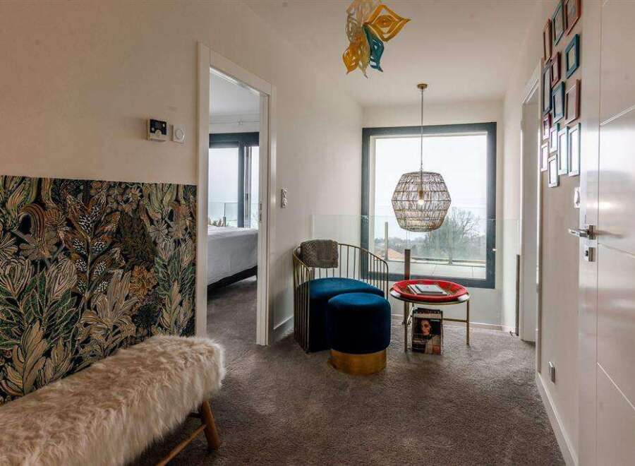 This stunning property boasts a spacious hallway with a unique patterned wall, plush seating area, and large windows offering breathtaking views.