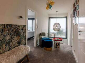 This stunning property boasts a spacious hallway with a unique patterned wall, plush seating area, and large windows offering breathtaking views.