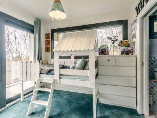 Charming child's bedroom with built-in bunk bed, ample storage, and sliding door access to bathroom.