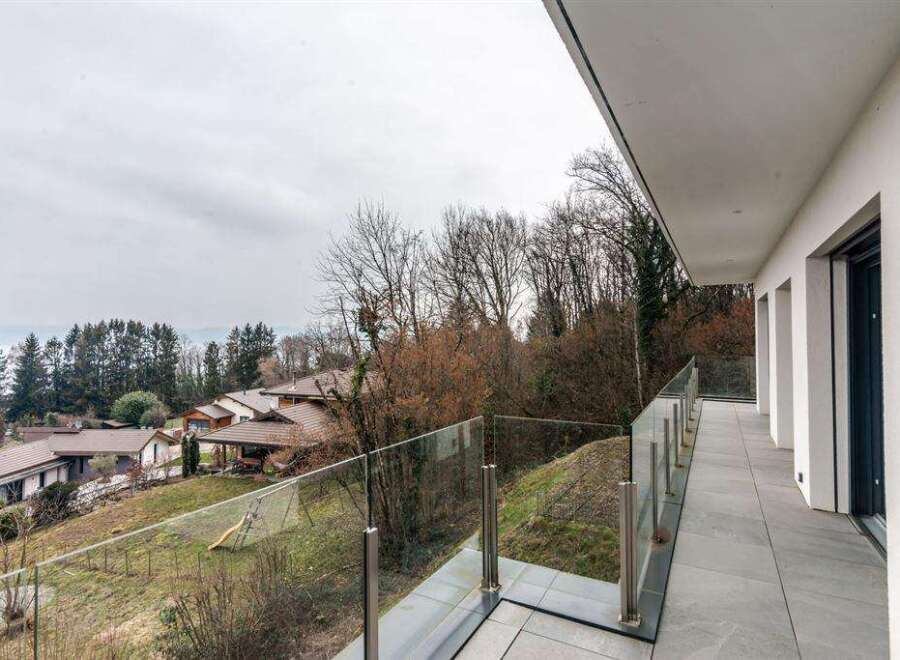 Modern balcony with glass railings offering panoramic views of the surrounding landscape.