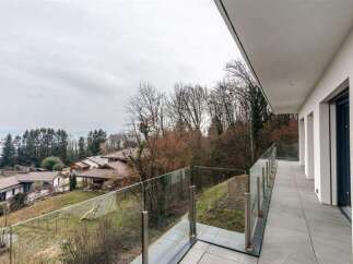 Modern balcony with glass railings offering panoramic views of the surrounding landscape.