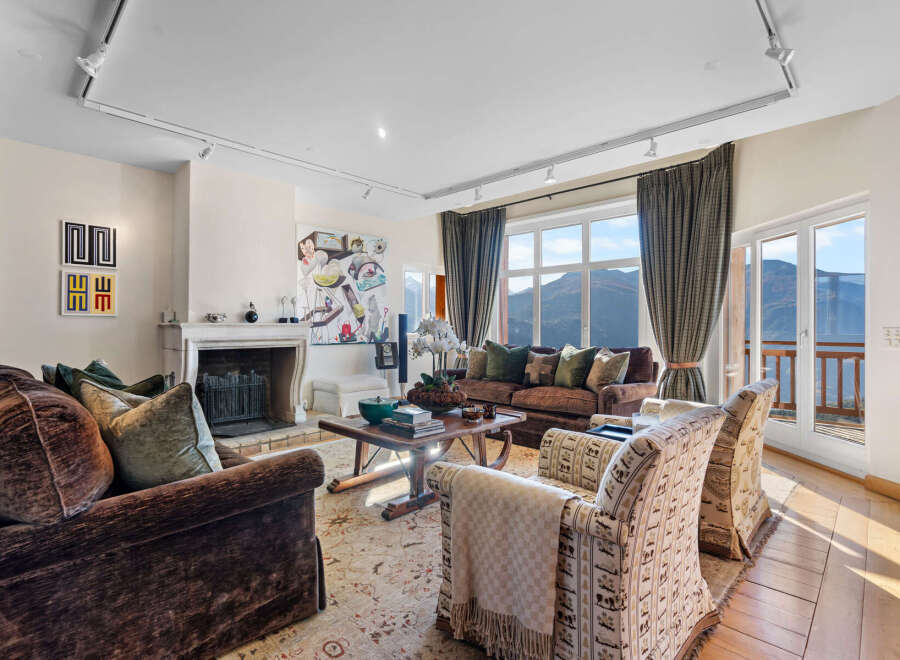 This luxurious living room boasts stunning mountain views through expansive windows and French doors, creating a bright and airy atmosphere.