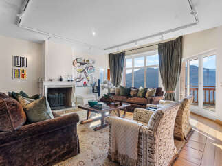 This luxurious living room boasts stunning mountain views through expansive windows and French doors, creating a bright and airy atmosphere.