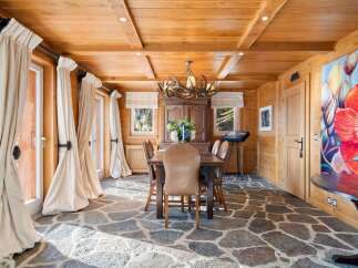This stunning dining room boasts a rustic-chic design with a wood-paneled ceiling, stone flooring, and large windows that let in plenty of natural light.