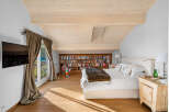 This luxurious bedroom boasts a stunning wooden ceiling, large windows offering scenic views, and ample built-in bookshelves.