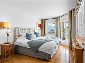 This luxurious bedroom boasts stunning lake views from its large windows and patio doors.