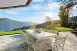 Luxury mountain retreat with expansive patio featuring a large stone table and ornate chairs, perfect for al fresco dining while enjoying breathtaking views.