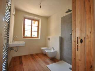 This charming bathroom features a rustic wooden floor and a bright window that fills the space with natural light.