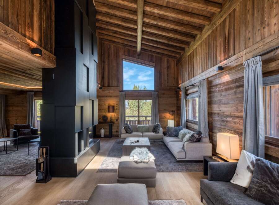 Experience luxury living in this stunning chalet, featuring a cozy living room with a fireplace and comfortable seating.