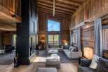 Experience luxury living in this stunning chalet, featuring a cozy living room with a fireplace and comfortable seating.