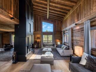 Experience luxury living in this stunning chalet, featuring a cozy living room with a fireplace and comfortable seating.
