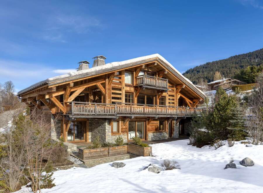 Experience luxury living in this stunning wooden chalet nestled in a snowy landscape.