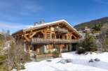 Experience luxury living in this stunning wooden chalet nestled in a snowy landscape.