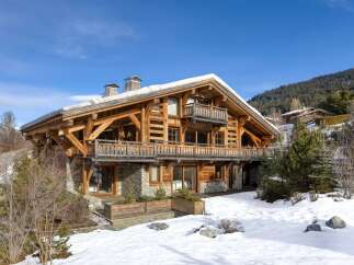 Experience luxury living in this stunning wooden chalet nestled in a snowy landscape.
