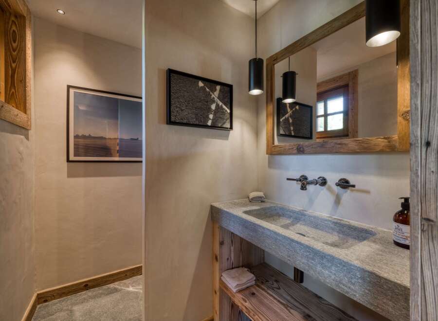This rustic bathroom features a unique stone sink and wooden accents, creating a warm and inviting atmosphere.