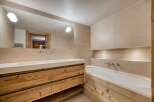 This luxurious bathroom features a stunning wooden vanity with ample storage and a sleek, modern design.