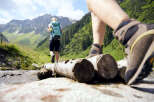 Explore the beauty of nature with this stunning image of hikers crossing a wooden bridge.