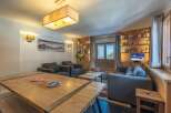 This stunning apartment boasts a spacious living area with comfortable seating, a large wooden dining table, and built-in bookshelves.