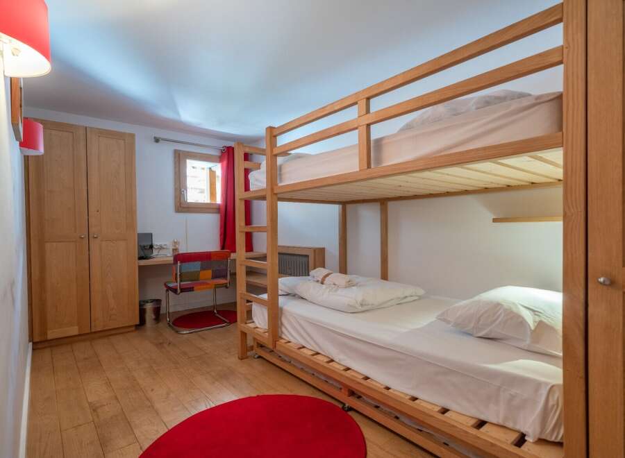Cozy bunk bed room with hardwood floors and red accents.