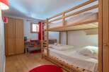 Cozy bunk bed room with hardwood floors and red accents.