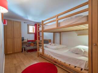 Cozy bunk bed room with hardwood floors and red accents.