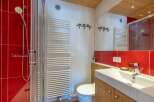 This stunning bathroom boasts a modern design with red tile accents and a sleek glass shower enclosure.