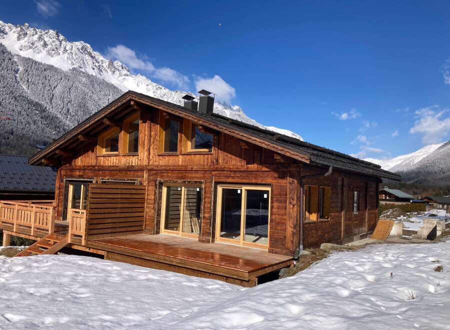 This stunning chalet boasts a spacious wooden deck, perfect for enjoying the breathtaking mountain views.