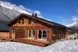 This stunning chalet boasts a spacious wooden deck, perfect for enjoying the breathtaking mountain views.