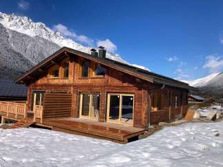 This stunning chalet boasts a spacious wooden deck, perfect for enjoying the breathtaking mountain views.