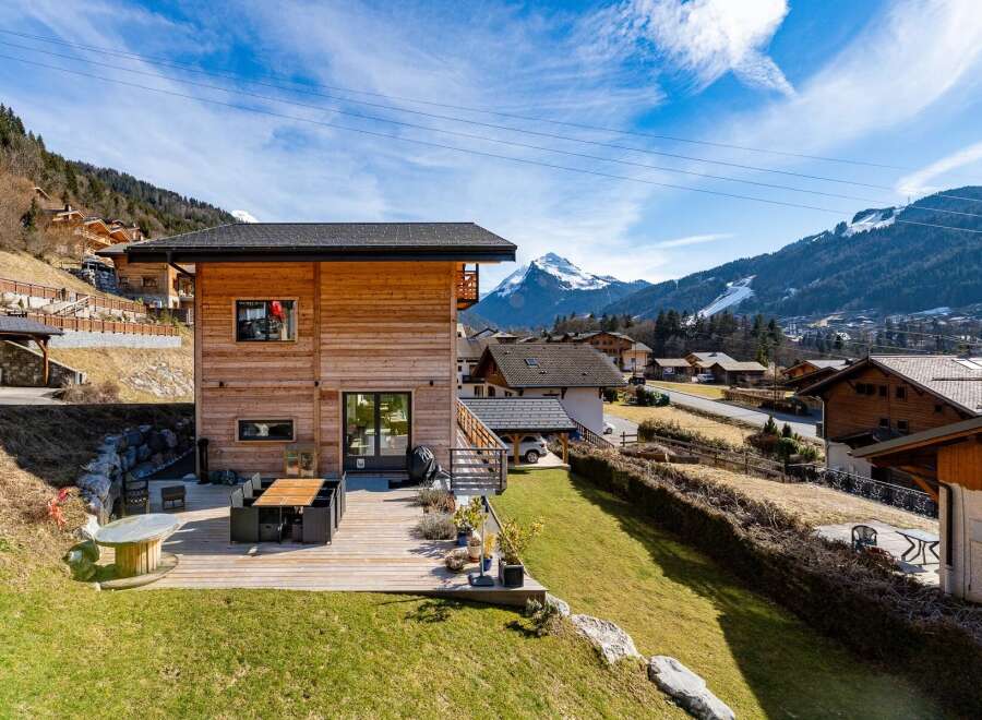 Experience luxury mountain living in this stunning wooden chalet, featuring a spacious outdoor deck perfect for al fresco dining with breathtaking alpine views.