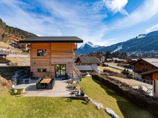 Experience luxury mountain living in this stunning wooden chalet, featuring a spacious outdoor deck perfect for al fresco dining with breathtaking alpine views.