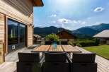 Enjoy breathtaking mountain views from this stunning property's expansive wooden deck, perfect for al fresco dining.