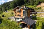 Experience luxury mountain living in this stunning chalet, featuring a modern design with warm wood accents and stone detailing.
