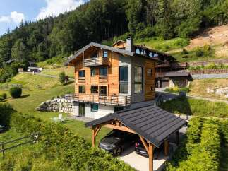 Experience luxury mountain living in this stunning chalet, featuring a modern design with warm wood accents and stone detailing.