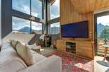 Experience breathtaking mountain views from this modern living room, featuring a large sectional sofa and a cozy wood-burning stove.