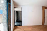 Modern minimalist interior with sleek glass door and hardwood floors.
