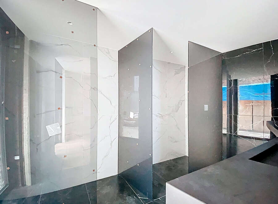 Luxury bathroom with marble walls and glass partitions.